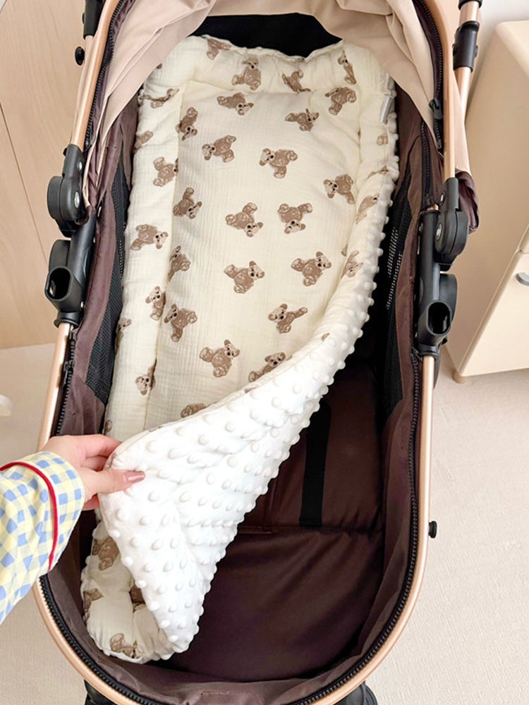 pettena terra専用、カート内部に敷いたクマ柄マットの拡大図。手でめくって裏面の白いドットボア素材を見せており、表裏で異なる肌触りが確認できるリバーシブル仕様です。