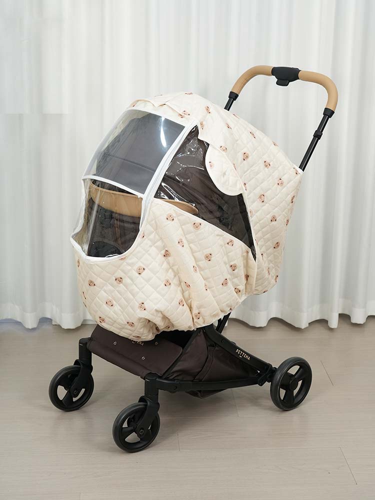 斜め前方から捉えたPETTENAのペットカートカバー。サイドのメッシュ窓やくま柄のキルティングが見える、防寒・防风対策を施したお洒落なフルカバーの外観。