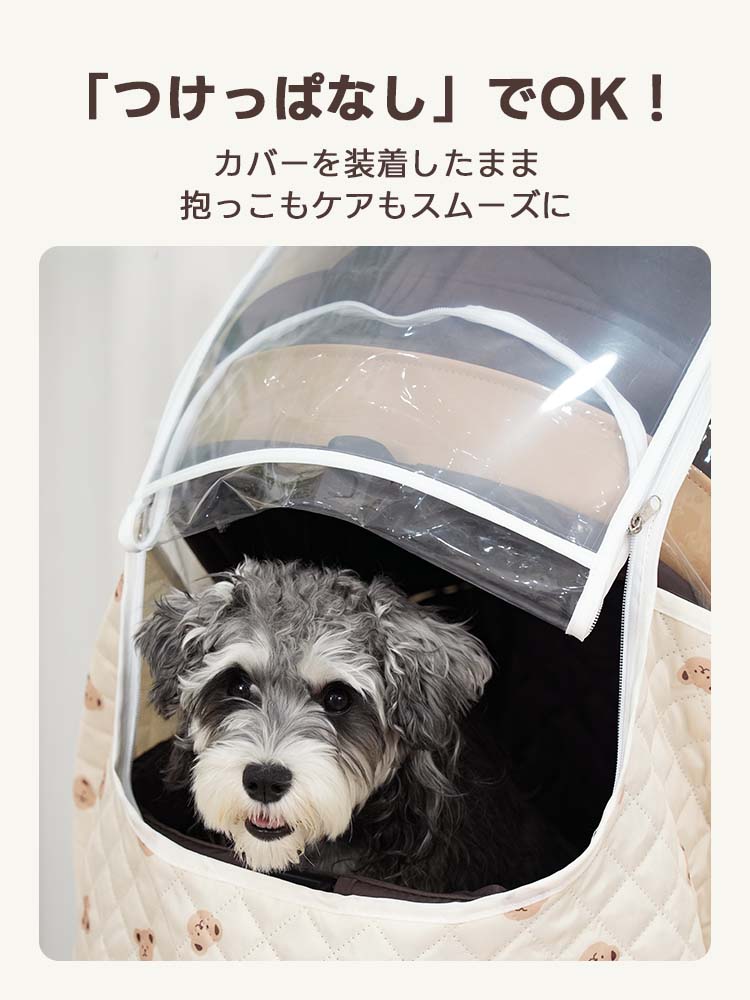 ミルクベージュのくま柄カバーの透明窓を開けて、顔を出すシュナウザーの様子。カバーを装着したまま愛犬を抱き上げたりケアしたりできる「つけっぱなしOK」な利便性を表現。