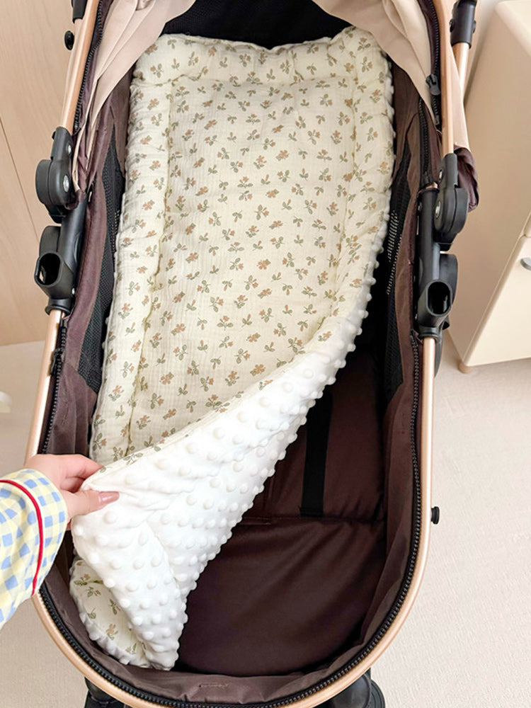 PETTENA、TERRA専用。カート内部に敷いた花柄マットの拡大図。手でめくって裏面の白いドットボア素材を見せており、表裏で異なる肌触りが確認できるリバーシブル仕様です。