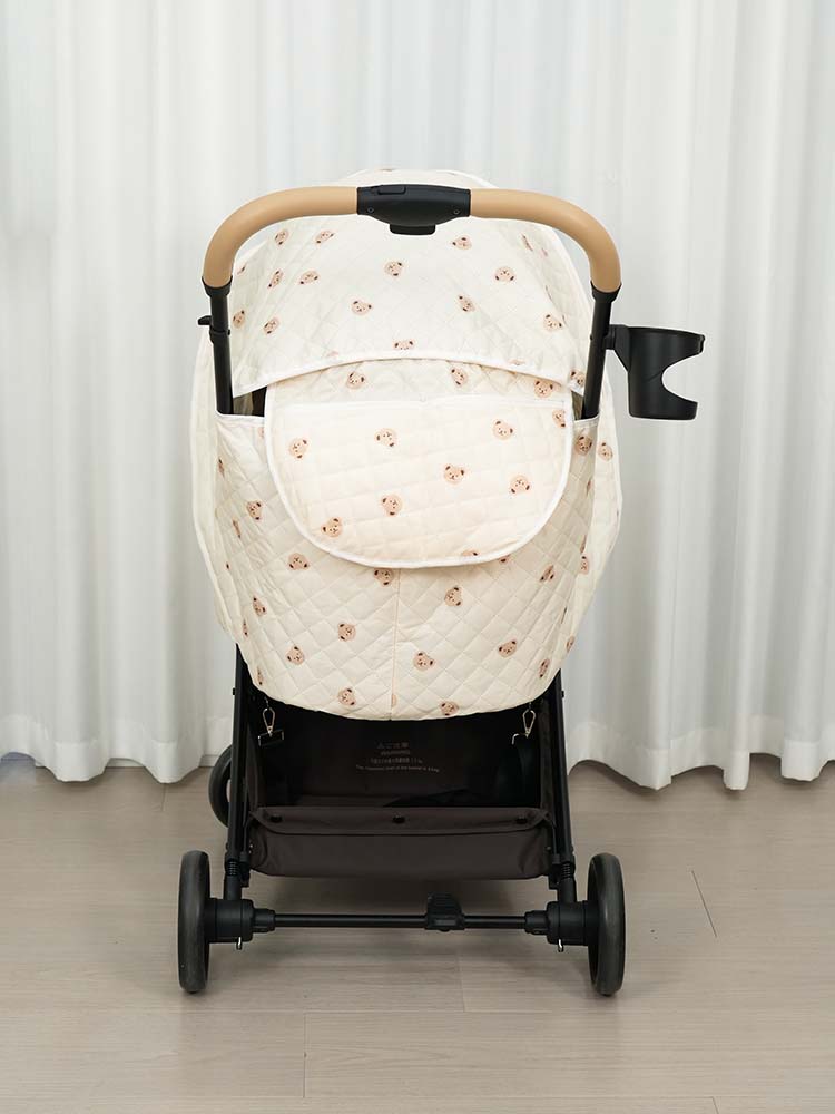 MILOU/ORION専用カバーの背面ショット。ベージュのくま柄キルティングがハンドル下まで隙間なく包み込み、後ろからの冷気を完全にシャットアウトする様子を表現。