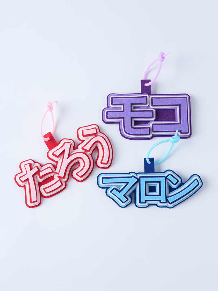 ひらがなやカタカナで作成された、色鮮やかなフェルト製名入れチャームのバリエーション。赤、紫、青など、文字数(2文字・3文字)や好みの色を組み合わせて自分だけのデザインを楽しめます。もこもこした厚みのある質感が、視認性と可愛さを両立します。