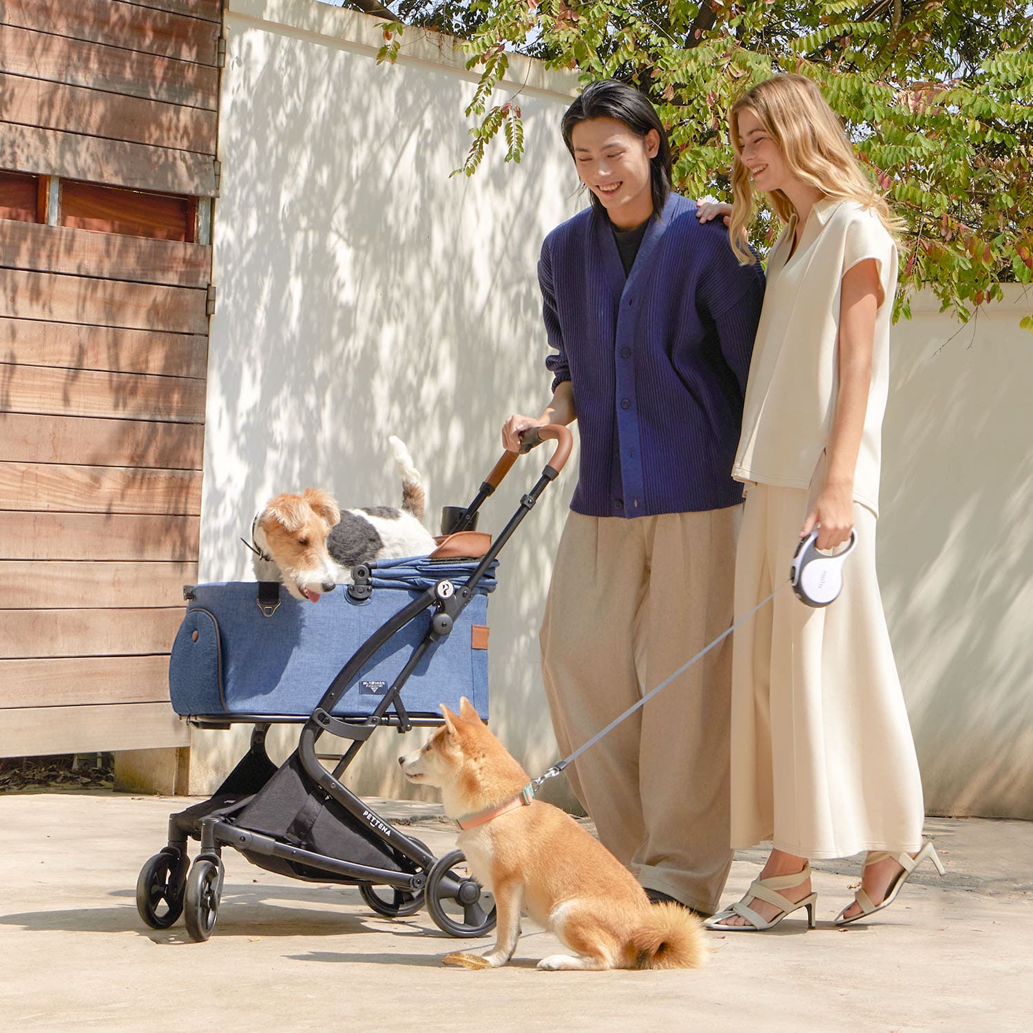PETTENA milou 2人がネービーペットベカートと2匹の犬と散歩する様子。ペットとのお出かけを快適にする機能的ペットカート。