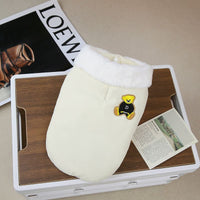 清潔感のあるオフホワイトの生地に、真っ白なボア襟を合わせた犬用防寒ジャケット。黄色いクマのワッペンがポイントで、背中のリード穴からハーネスを通せる設計です。