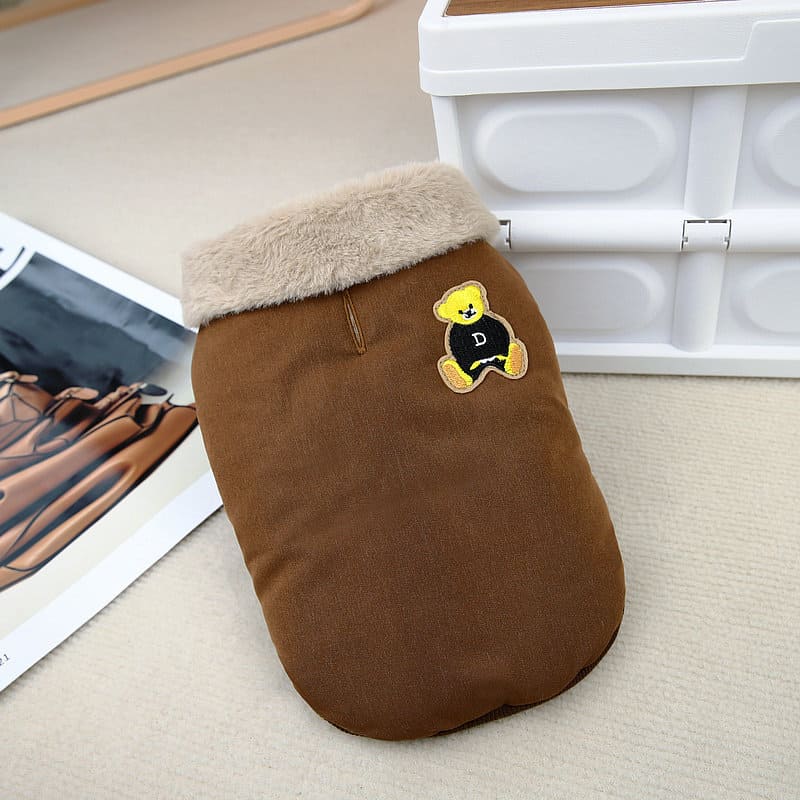 こっくりとしたコーヒー色の生地に、ベージュのボア襟とクマのワッペンが映える犬用ジャケット。背中にはリードを通すためのスリットがあり、実用的なディテールを紹介。